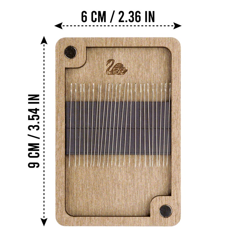 May include: A wooden needle storage box with a magnetic closure. The box is 6 inches wide and 9 inches tall. The box has a swan logo on the front and is filled with needles.