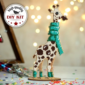 May include: DIY kit for a wooden giraffe figurine with a brown and white spotted pattern. The giraffe is wearing a turquoise scarf and has turquoise boots. The kit includes all the necessary materials to create the figurine.
