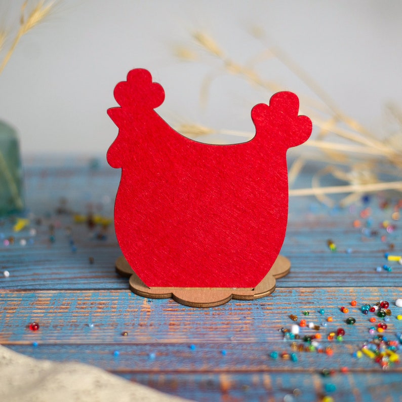 Puede incluir: Porta servilletas de pollo de fieltro rojo con un dise&ntilde;o sencillo. El porta servilletas est&aacute; hecho de madera y tiene la forma recortada de un pollo.