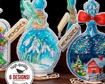 May include: Six different cross stitch patterns of glass bottles with various scenes inside. Each bottle has a tag that says "Memories". The bottles are on wooden stands. The image also includes a circular sticker that says "high quality 6 DESIGNS! DIY kits".