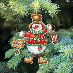 May include: A snowman Christmas ornament with a red and green scarf, a red hat, and a sign that says "Happy New Year".