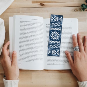 May include: A blue and white snowflake patterned bookmark. The bookmark is made of fabric and has a fringed edge.