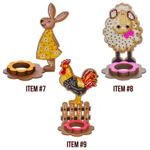 Pu&ograve; includere: Tre porta uova di Pasqua in legno con diversi disegni di animali. Il primo porta uova presenta un coniglietto giallo, il secondo una pecora marrone e il terzo un gallo con cresta e coda rosse. Ogni porta uova ha un anello rosa per tenere un uovo.