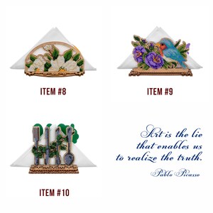 May include: Three wooden napkin holders with different embroidered designs. The first holder features a white flower design, the second has a blue bird and purple flowers, and the third has a green design with a fork, knife, and spoon.