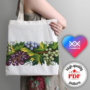 May include: A white tote bag with a cross-stitch design of grapes and leaves. The bag has a handle and is made of canvas. The image also includes a heart with a needle and thread design and a circle with the text "high quality PDF pattern".