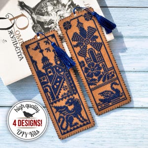 Puede incluir: Dos marcapáginas rectangulares de color tostado con patrones de punto de cruz azul oscuro. Uno muestra un castillo y un dragón, el otro un molino, flores y un cisne. Cada marcapáginas tiene un agujero en la parte superior con una borla azul.