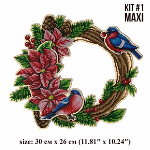 May include: A Christmas wreath kit with a wooden base, featuring poinsettia flowers, pine branches, red berries, and two blue birds. The kit is labeled "KIT #1 MAXI" and measures 11.81 inches by 10.24 inches.