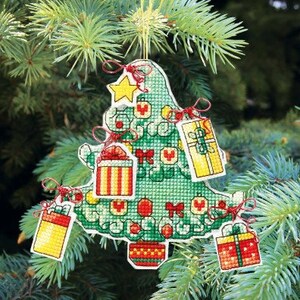 May include: A green felt Christmas tree ornament with red and white ribbon accents. The tree is decorated with small red and white ornaments and four small gift boxes with red, white, and yellow designs.