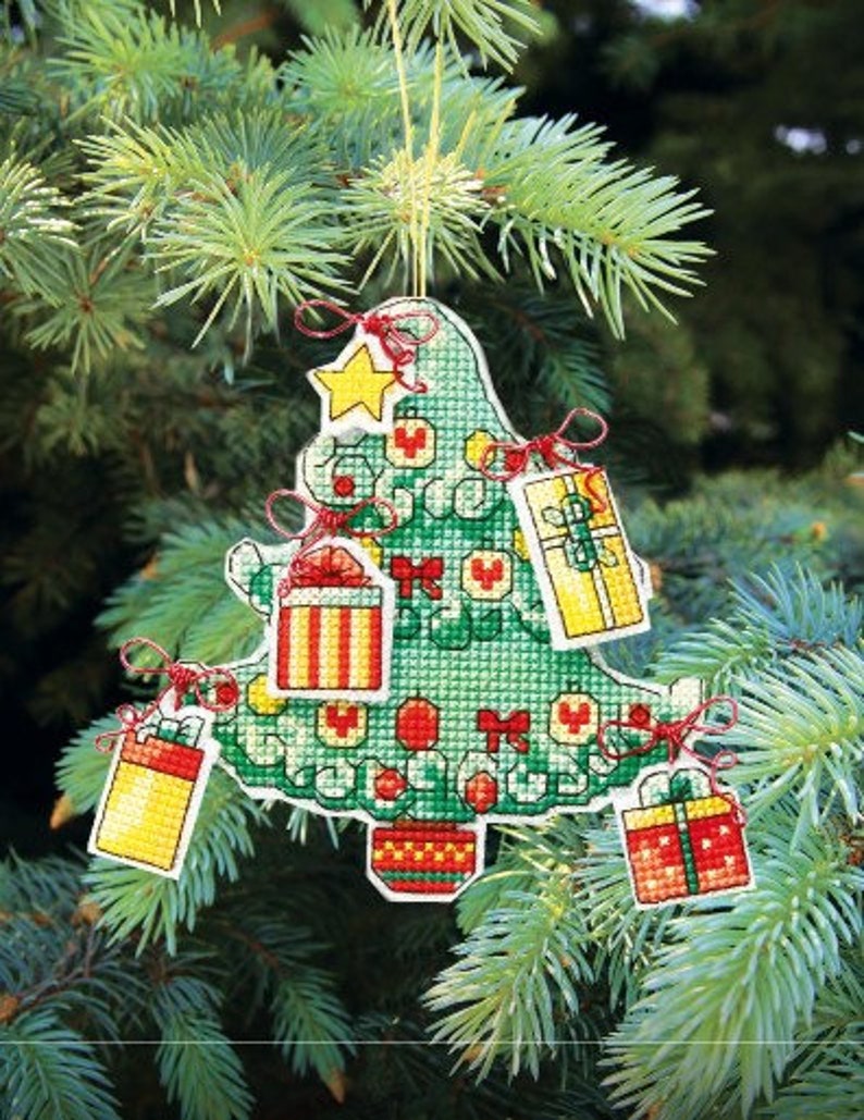 May include: A green felt Christmas tree ornament with red and white ribbon accents. The tree is decorated with small red and white ornaments and four small gift boxes with red, white, and yellow designs.