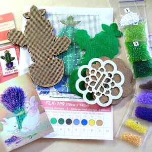 May include: Crafting kit with wooden cactus and flower shapes, green felt cutouts, and a cross-stitch pattern. Includes small bags of beads in various colors, a card with lavender and rabbits, and a card with a cactus.