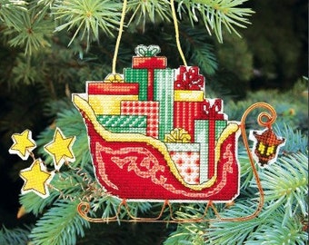 May include: A red and gold sleigh filled with colorful wrapped gifts, a Christmas ornament.