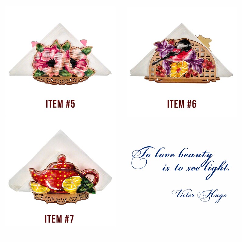 May include: Three wooden napkin holders with embroidered designs. The first holder features pink flowers, the second has a bird and berries, and the third has a red teapot with lemons.