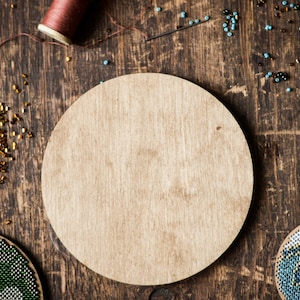 May include: A wooden round craft base with a natural wood finish. The base is surrounded by colorful beads and a spool of thread.