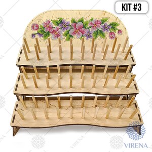 May include: A three-tier wooden embroidery floss organizer with a floral design on the top tier. The organizer has a total of 90 dowels for holding floss spools. KIT #3 is printed on the top right corner of the image.