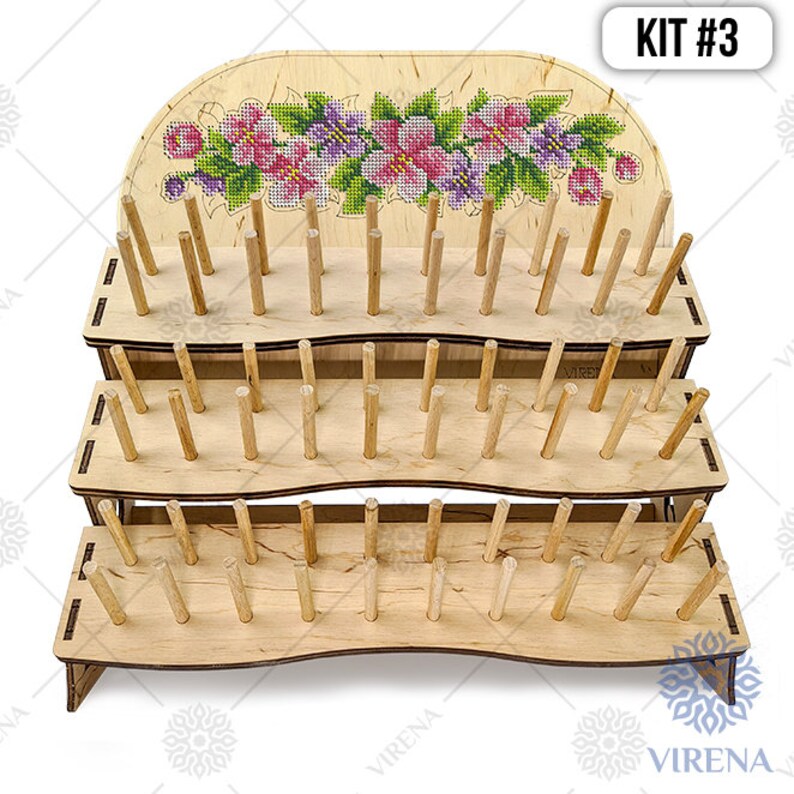 May include: A three-tier wooden embroidery floss organizer with a floral design on the top tier. The organizer has a total of 90 dowels for holding floss spools. KIT #3 is printed on the top right corner of the image.