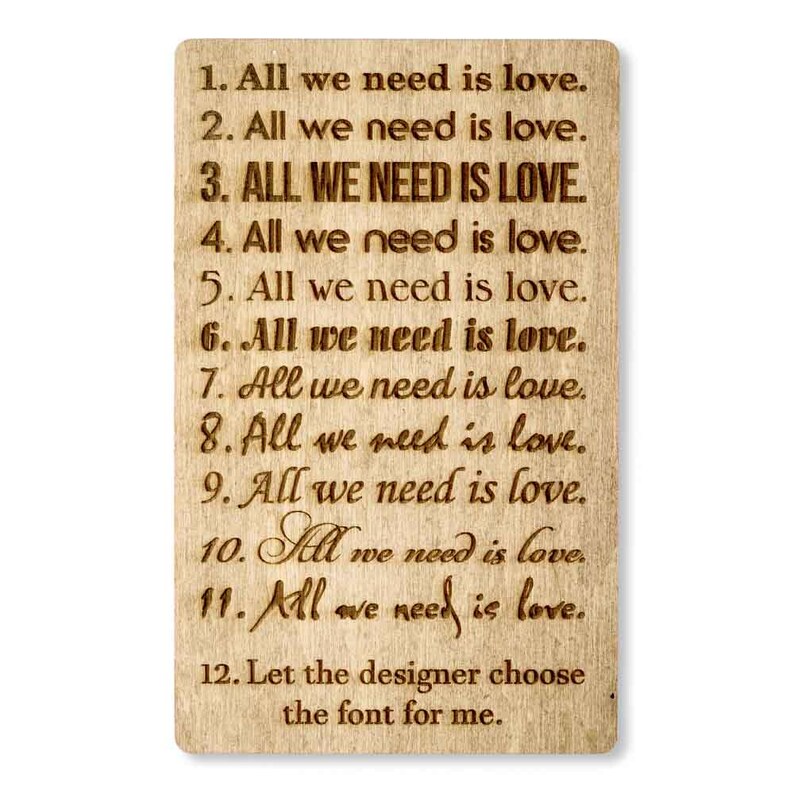 May include: A wooden sign with the text "All we need is love." repeated 11 times in different fonts. The text "Let the designer choose the font for me." is at the bottom of the sign.