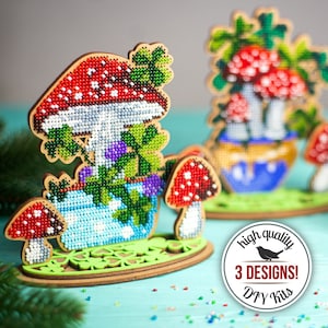 May include: Wooden DIY kits featuring mushroom designs with red and white caps, green leaves, and blue and purple accents. The kits are on a green base with a clover design. The image includes a circular graphic that says "high quality 3 DESIGNS! DIY Kits."