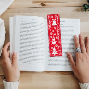 May include: Red and white Christmas bookmark with a snowman, a Christmas tree, and a bell. The bookmark says "Merry Christmas" in white letters.