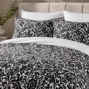May include: A bedding set featuring a black and white damask pattern. The set includes a comforter and two matching pillow shams, all decorated with an intricate, repeating floral and leaf motif. The bedding is displayed on a bed.
