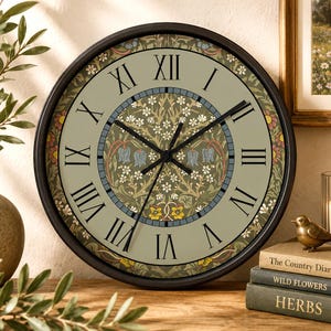May include: A round wall clock with a black frame and a light olive green face featuring black Roman numerals. The center displays a detailed botanical pattern with small white flowers, blue bell-shaped blossoms, and yellow accents.