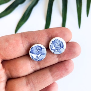 May include: A pair of blue and white ceramic stud earrings with a floral design.