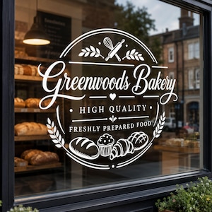 May include: A white circular window decal featuring the text Greenwoods Bakery, HIGH QUALITY, and FRESHLY PREPARED FOOD. The design includes illustrations of a whisk, rolling pin, wheat stalks, a heart, a loaf of bread, a muffin, and a croissant.