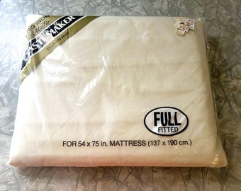 May include: A cream-colored full fitted sheet in original plastic packaging. The label reads "No Iron Muslin," "Pastemaker by J.P. Stevens," and "Full Fitted for 54 x 75 in. mattress." The packaging includes a small price tag in the corner.
