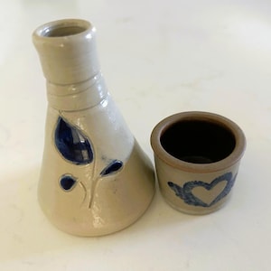 May include: A set of three ceramic mugs with a speckled, matte finish in cream, light grey, and dark grey. Each mug has a simple, minimalist design and a rounded handle.