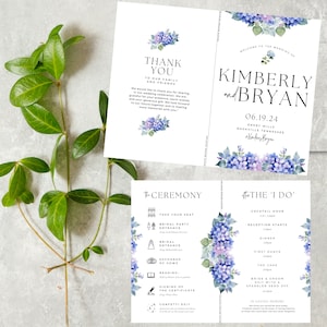 May include: Wedding invitation suite with blue and purple hydrangea floral designs. The cards include the ceremony and reception details, along with the couple's names, Kimberly and Bryan, and the date 06.19.24.