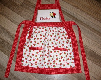 cute red and white children's apron with strawberry motifs in size 92 to 122