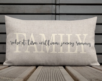May include: A beige throw pillow with the word "FAMILY" in white lettering and the names "Robert, Lisa, William, Jenny, Sammy" in gray lettering.