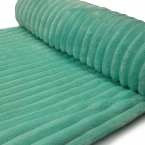 May include: A roll of soft, mint green corduroy fabric. The fabric has a ribbed texture with vertical lines. The material is plush and appears to be a medium weight. The fabric is rolled up on one end.