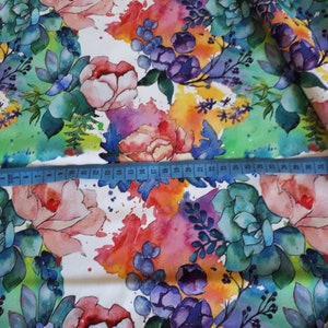 Peut inclure: Tissu floral aquarelle sur fond blanc. Le tissu pr&eacute;sente un motif color&eacute; de fleurs et de feuilles roses, violettes, bleues, vertes et jaunes. Un m&egrave;tre ruban est plac&eacute; sur le tissu pour montrer l'&eacute;chelle.