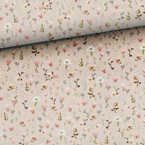 Pode incluir: Um tecido bege com um padr&atilde;o repetitivo de pequenas flores rosa e brancas. O tecido tem uma textura sutil.