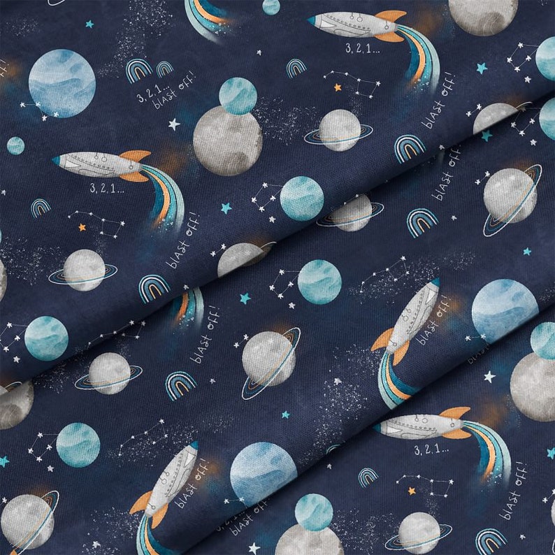 Pu&ograve; includere: Un tessuto blu navy con un motivo ripetuto di pianeti, stelle, arcobaleni e razzi. Il testo "3,2,1... blast off!" &egrave; ripetuto in tutto il motivo.