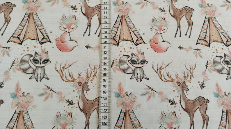 May include: White fabric with a repeating pattern of woodland animals, including foxes, deer, and raccoons. The animals are wearing floral crowns and there are teepees and arrows in the pattern.