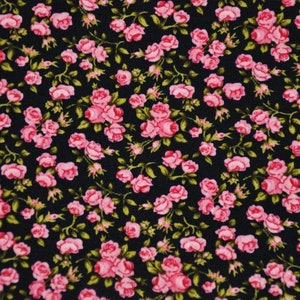 Könnte beinhalten: Ein schwarzer Stoff mit einem rosafarbenen Blumenmuster. Der Stoff ist mit kleinen rosafarbenen Rosen mit grünen Blättern bedeckt.