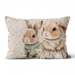 Pode incluir: Dois coelhos marrons com detalhes florais. Um coelho est&aacute; vestindo um su&eacute;ter verde e o outro um vestido rosa. Os coelhos est&atilde;o em um fundo bege com um padr&atilde;o floral.
