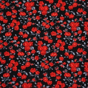 Könnte beinhalten: Ein schwarzer Stoff mit einem sich wiederholenden Muster aus roten Rosen. Die Rosen sind klein und haben ein einfaches Design.
