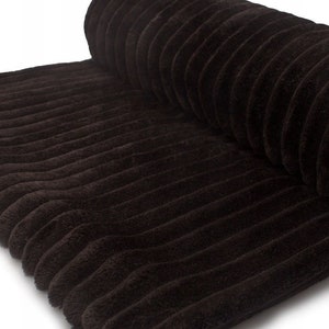 May include: A roll of dark brown corduroy fabric. The fabric has a ribbed texture with vertical lines. The corduroy is a soft, plush material, and the roll is partially unrolled, revealing the texture.