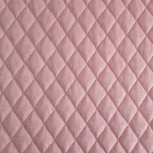 Könnte beinhalten: Nahaufnahme eines rosa gesteppten Stoffes mit einem Rautenmuster.
