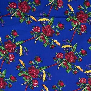 May include: A blue fabric with a repeating pattern of red roses, green leaves, and yellow wheat stalks.