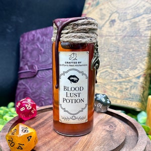 Könnte beinhalten: Eine braune Glasflasche mit der Aufschrift "BLOOD LUST POTION" mit einem dunkelroten Wachssiegel und einem dekorativen Anhänger. Das Etikett lautet "Crafted by Griffon's Nest Alchemists" und zeigt Lippen. Die Flasche steht auf einem Holzständer mit Würfeln.