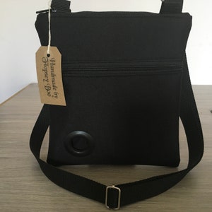 May include: Black crossbody bag with a zipper closure and a metal ring on the front. The bag has a brown tag that says "Handmade by Hopsey Boo."
