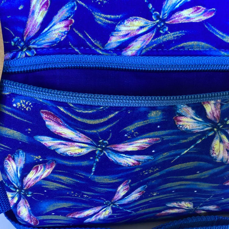 May include: A blue fabric bag with a zipper closure. The fabric has a pattern of colorful dragonflies on a blue background with gold accents.