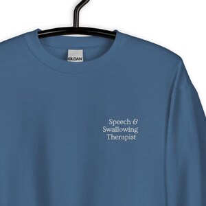 May include: A blue sweatshirt with the text "Speech & Swallowing Therapist" embroidered on the front.
