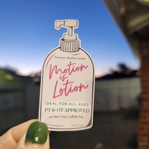 Puede incluir: Una pegatina rosa y blanca con un dibujo de una botella de loción. La pegatina dice "Premium Quality Goods Motion is Lotion Ideal para todas las edades PT & OT APPROVED paraben free | sulfate free 00 FL OZ"