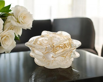 May include: A clear glass rose-shaped decorative bowl with gold accents. The bowl is sitting on a dark surface.