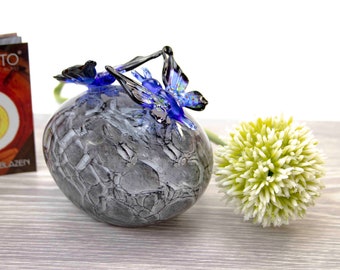 May include: A glass paperweight with a gray and white marbled design and two blue glass butterflies on top.