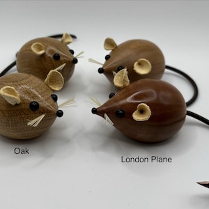 Puede incluir: Cuatro figuras de rat&oacute;n de madera con cuerpos lisos y redondeados, ojos de cuentas negras y bigotes finos y claros. Dos ratones est&aacute;n etiquetados como Oak, mostrando una veta de madera clara, y dos como London Plane, con un acabado pulido oscuro.